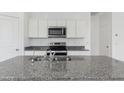 Modern kitchen featuring stainless steel appliances, granite countertops, and white cabinets for a clean aesthetic at 1408 W Hess Ave, Coolidge, AZ 85128