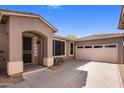 Attractive home exterior showing front door, tan stucco, tile roof, desert landscaping, and attached two car garage at 2610 W Sat Nam Way, Phoenix, AZ 85086