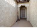 Inviting covered home entrance showcasing neutral toned walls and secured front door at 27291 W Mohawk Ln, Buckeye, AZ 85396