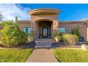 Welcoming entrance with a decorative iron door, potted plants, and stone accents at 3042 W Windsong Dr, Phoenix, AZ 85045
