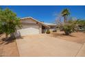 Single-story home with a two car garage, desert landscaping and a large concrete driveway at 3136 W Voltaire Ave, Phoenix, AZ 85029