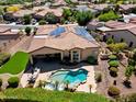 Aerial view of backyard with pool, patio seating, green space and solar panels on the roof at 12976 W Plum Rd, Peoria, AZ 85383