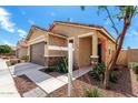 Landscaped front yard and covered entrance featuring stone pillar accents at this lovely home at 14355 W Valentine St, Surprise, AZ 85379