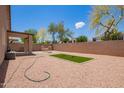Expansive backyard featuring a covered patio, gravel landscape, and a vibrant tree, perfect for outdoor relaxation at 16274 N 138Th Ln, Surprise, AZ 85374