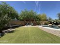 Lush backyard featuring a pool, seating, turf, mature landscaping, and rock details at 20426 N Alma Dr, Maricopa, AZ 85138