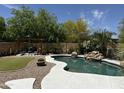Resort style pool with rock waterfall feature, pergola with seating, and lush landscaping at 20426 N Alma Dr, Maricopa, AZ 85138