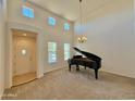 Bright living room featuring soaring ceilings, neutral walls and carpet, and a grand piano at 20472 W Daniel Pl, Buckeye, AZ 85396