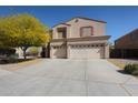 Tan two-story home featuring a spacious three-car garage and a mature tree in the front yard at 23104 W Kimberly Dr, Buckeye, AZ 85326