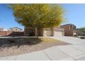 View of a tan two-story home with a mature yellow tree on a stone-covered front yard at 23104 W Kimberly Dr, Buckeye, AZ 85326