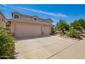 Home featuring a three-car garage, large driveway, and desert landscaping at 44041 W Bailey Dr, Maricopa, AZ 85138