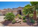 Landscaped front yard featuring gravel, rock features, and vibrant desert plants at 44041 W Bailey Dr, Maricopa, AZ 85138