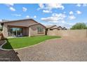A spacious backyard with lush green grass, neutral gravel area, and a covered patio with outdoor seating at 9147 W Minnezona Ave, Phoenix, AZ 85037
