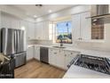 Well-lit modern kitchen featuring stainless steel appliances, white cabinetry, and hardwood floors at 942 S Ash Ave # 104, Tempe, AZ 85281