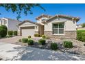 Charming single-story home featuring a two-car garage, stone accents, and meticulously landscaped front yard under blue skies at 9510 E Theia Dr, Mesa, AZ 85212