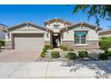 Charming single-story home featuring a two-car garage, stone accents, and meticulously landscaped front yard under blue skies at 9510 E Theia Dr, Mesa, AZ 85212