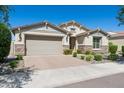 Charming single-story home featuring a two-car garage, stone accents, and meticulously landscaped front yard under blue skies at 9510 E Theia Dr, Mesa, AZ 85212