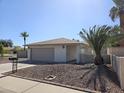 Charming single-story home featuring desert rock landscaping, a two car garage and healthy palm trees at 9612 N 52Nd Dr, Glendale, AZ 85302