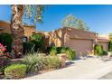 A single-story home with a two-car garage, showcasing mature trees and flowering shrubs for added curb appeal at 1010 E Lois Ln, Phoenix, AZ 85020