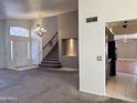 Bright living room with stairs, chandelier, tile entry, and an open view to the kitchen area at 11403 W Rosewood Dr, Avondale, AZ 85392