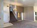 Spacious living area with neutral carpet, a chandelier, and a staircase leading to the upper level at 11403 W Rosewood Dr, Avondale, AZ 85392