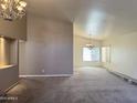 Open-concept living area featuring neutral walls, carpet, and an elegant chandelier over the dining space at 11403 W Rosewood Dr, Avondale, AZ 85392