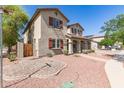 Lovely two-story home with well-manicured landscaping, including decorative rock and lush green bushes at 14440 W Cholla St, Surprise, AZ 85379