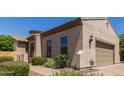 Exterior of a tan home with well-kept landscaping and brick paver driveway at 1824 N Red Clf, Mesa, AZ 85207