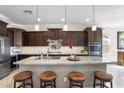 Modern kitchen features an island with seating, granite countertops, and stainless steel appliances at 31156 N 137Th Ln, Peoria, AZ 85383