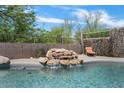 Backyard pool showcasing a serene rock waterfall feature surrounded by lush greenery and privacy fencing at 3812 N Barron --, Mesa, AZ 85207