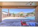 Covered patio overlooking the serene pool area, ideal for outdoor dining and relaxation at 43302 W Bunker Dr, Maricopa, AZ 85138