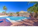 Backyard pool area featuring a small waterfall, mature palm trees, and privacy fence at 43302 W Bunker Dr, Maricopa, AZ 85138