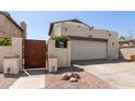 Home features a driveway leading to an attached two-car garage, complemented by landscaping and a wooden gate at 630 E Jensen St # 116, Mesa, AZ 85203