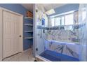 Walk-in shower boasts marble tiles, a blue mosaic bench, rainfall shower head, and a glass door at 6462 E Raftriver St, Mesa, AZ 85215
