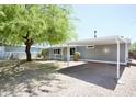 Side view of a gray home with a carport, desert landscaping and a large tree at 9733 E Baywood Ave, Mesa, AZ 85208