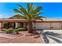 Inviting home with lush landscaping, a mature palm tree, tile roof, and three-car garage with an extended driveway at 10937 N Ventana W Dr, Peoria, AZ 85373