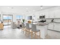 Bright, open-concept kitchen featuring white cabinets, stainless steel appliances, and a granite countertop island at 15627 W Hackamore Dr, Surprise, AZ 85387