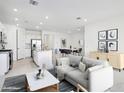 Spacious open-concept living room with modern furnishings, leading to a dining area and stylish kitchen at 15627 W Hackamore Dr, Surprise, AZ 85387