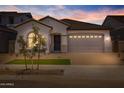Charming single-story home featuring a manicured front yard and a two-car garage at dusk at 15642 W Georgia Dr, Surprise, AZ 85379