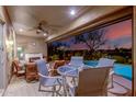 Cozy covered patio with outdoor seating and a fireplace, overlooking the pool area and serene landscape at 20558 N 263Rd Dr, Buckeye, AZ 85396