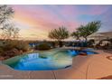 Inviting pool area featuring lush landscaping, lounge chairs, and a tranquil setting for relaxation at sunset at 20558 N 263Rd Dr, Buckeye, AZ 85396
