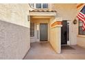 Close-up of a home's entryway with a gray door, American flag and textured walls at 250 W Juniper Ave # 22, Gilbert, AZ 85233
