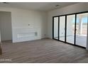 A spacious living room with modern wood look tile flooring, a custom fireplace wall, and large sliding glass doors to patio at 31060 N 213Th Dr, Wittmann, AZ 85361