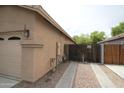 Side view of tan home with garage door and fenced side yard featuring desert landscaping at 7151 W Lamar Rd, Glendale, AZ 85303