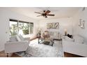 Bright living room featuring neutral furniture, ceiling fan, and a large window with a green outdoor view at 7521 S College Ave, Tempe, AZ 85283