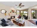 Bright living room with a stone fireplace, ceiling fan, and sliding doors to the outdoor patio at 7700 E Gainey Ranch Rd # 124, Scottsdale, AZ 85258
