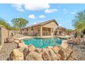 Beautiful backyard with a sparkling pool, rock features, and a covered patio at 8465 W Andrea Dr, Peoria, AZ 85383