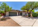 Beige single-story home featuring a large driveway and a well maintained front yard with mature trees at 8647 W Lariat Ln, Peoria, AZ 85383