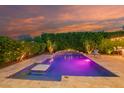 Inviting backyard pool with travertine surround, a swim-up table, and lush green landscaping at 15665 W Coronado Rd, Goodyear, AZ 85395