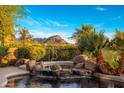 Beautiful pool featuring a rock waterfall and scenic mountain views in the background at 29412 N 108Th Pl, Scottsdale, AZ 85262