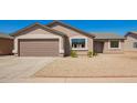 Tan single-story home features a two car garage and low maintenance gravel yard at 4542 N 86Th Dr, Phoenix, AZ 85037